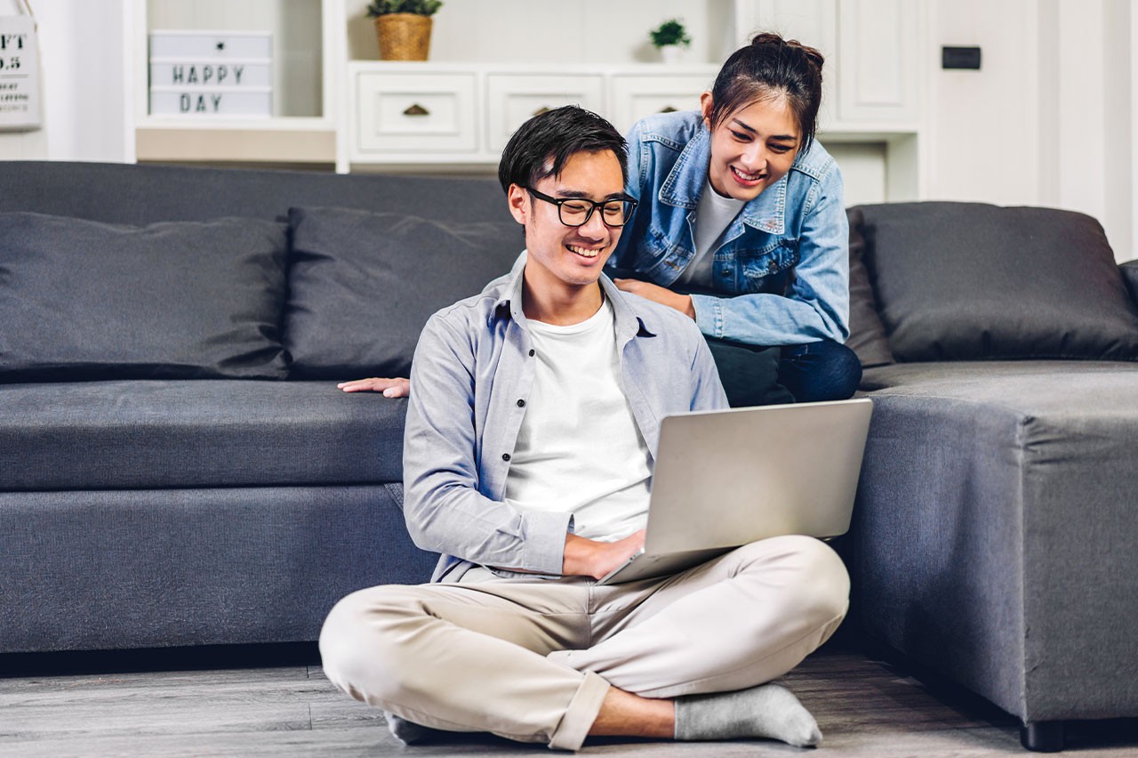Couple smiling while typing on a laptop