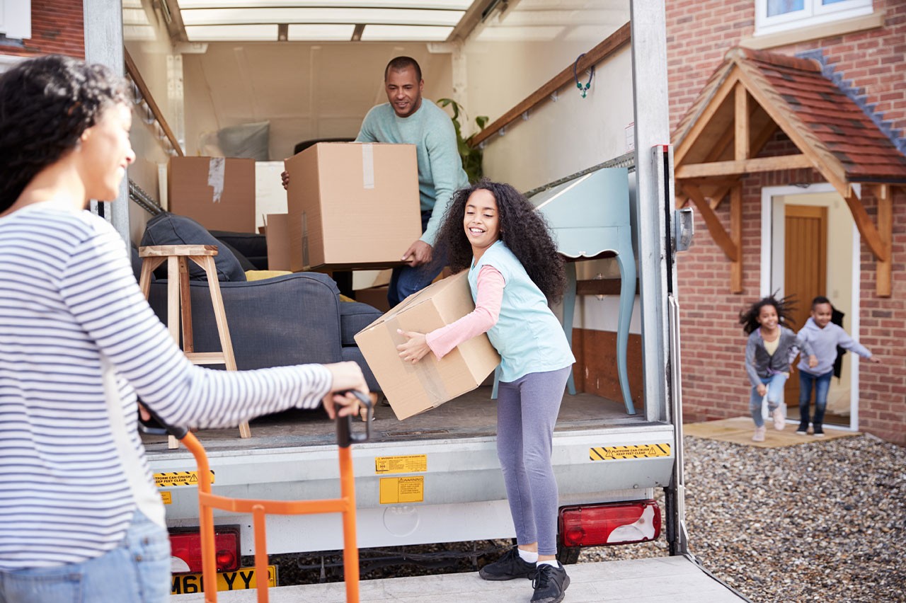 Family smiling while carrying boxes from a moving truck