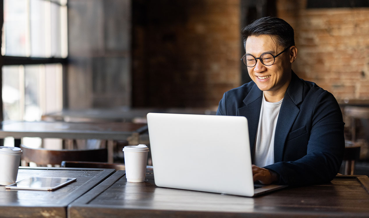 a man with glasses using a laptop at a desk