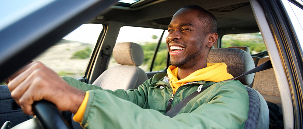 African American man smiling and driving a car