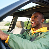 African American man smiling driving car