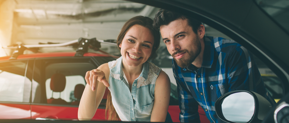 A couple pointing into a car.