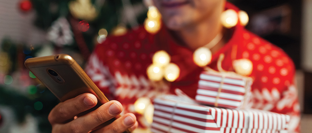 a person holding a mobile phone wearing a holiday sweater.