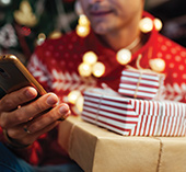 man holding gifts and looking at phone