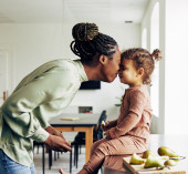 Mother playfully leaning her forehead on daughter's forehead while smiling