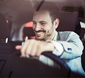 Man smiling in car while pressing buttons on dashboard 