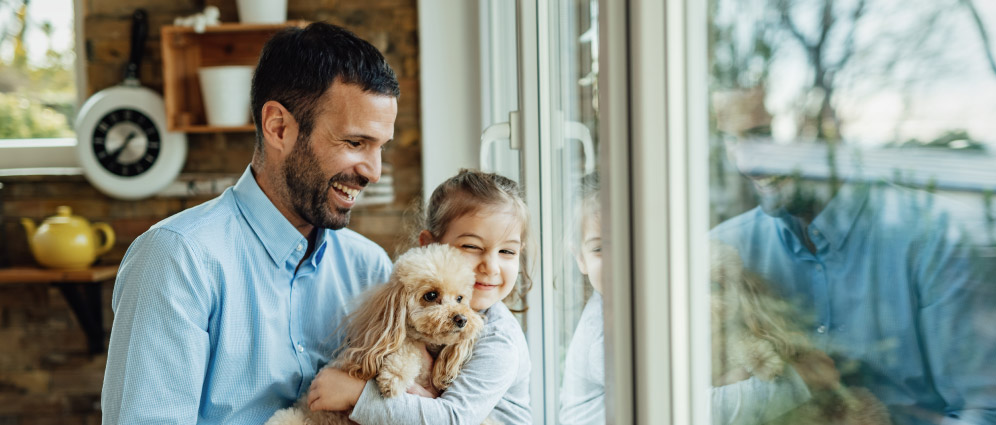 Father and daughter smiling while holding a puppy