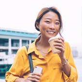 woman smiling holding phone and coffee