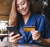 Woman smiling looking at her phone and credit card