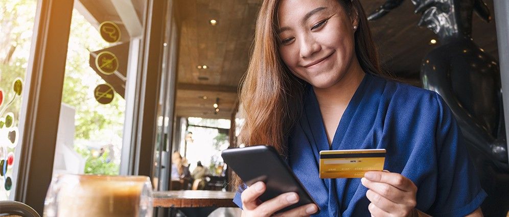 Woman smiling holding credit card and a phone