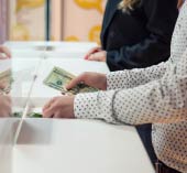 Man standing at bank teller counter with money in hand