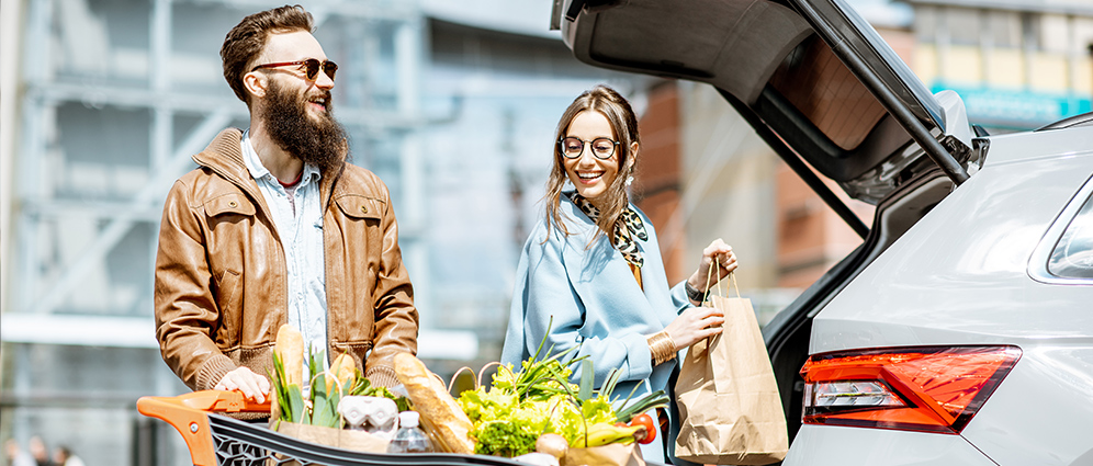 Happy couple packing their car with groceries