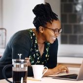 African American woman smiling looking at her checking account on laptop