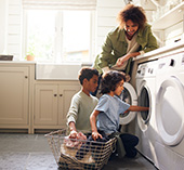 Man with kids doing laundry in energy efficient washer and dryer