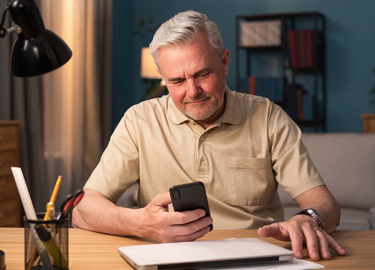 Senior man looking at phone smiling