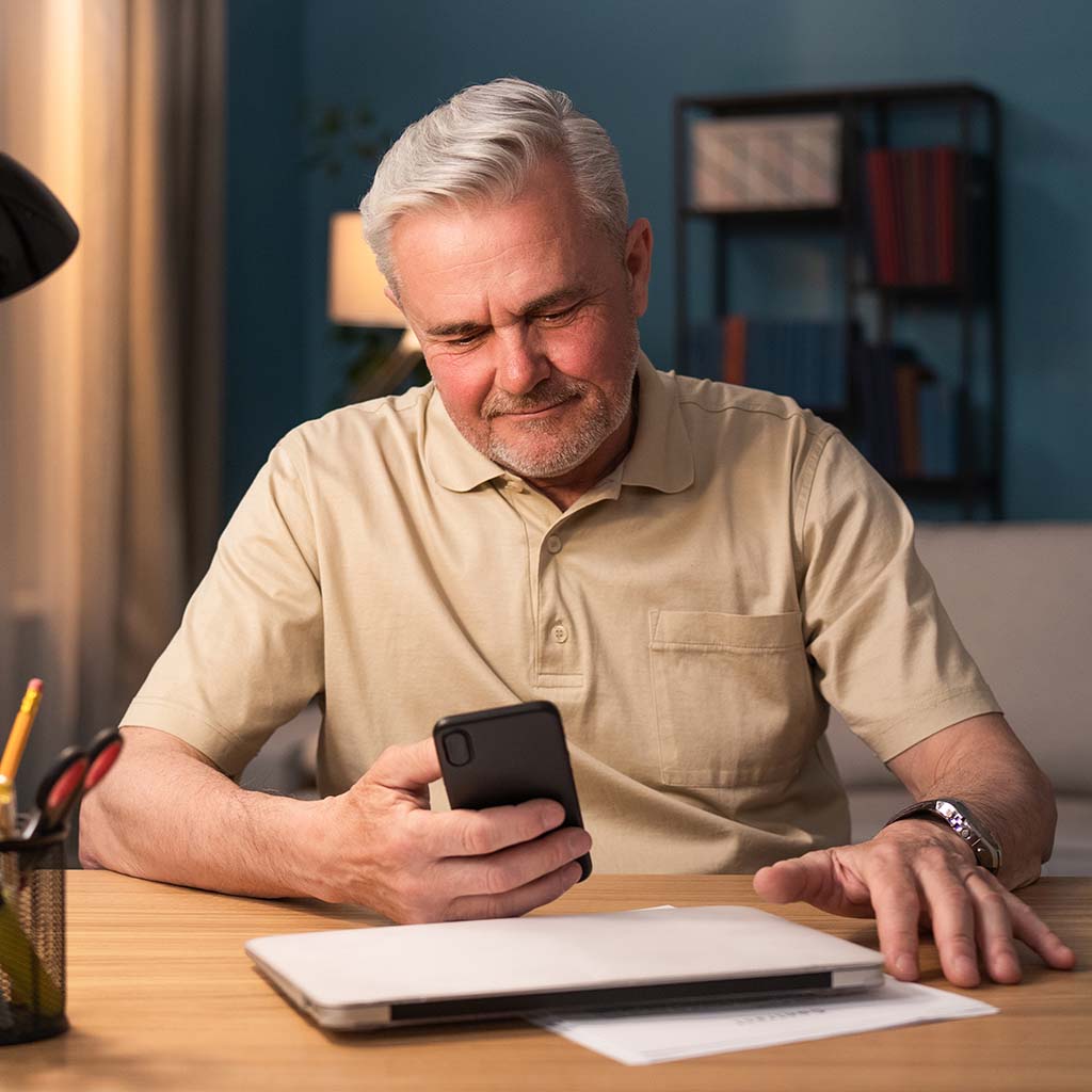 Senior man looking at phone smiling