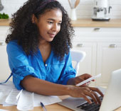 Woman sitting at laptop holding credit card 