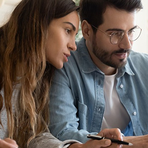 A man and woman seated looking at a computer screen.