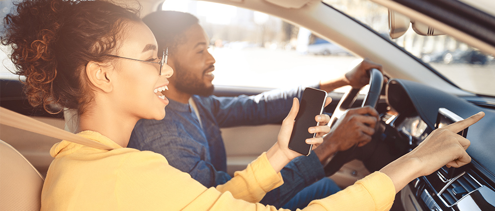 Man and woman inside car smiling