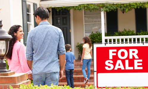 happy family in front of a home for sale