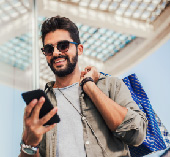 Smiling man carrying bag and looking at phone