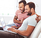 Guys smiling looking at a computer.