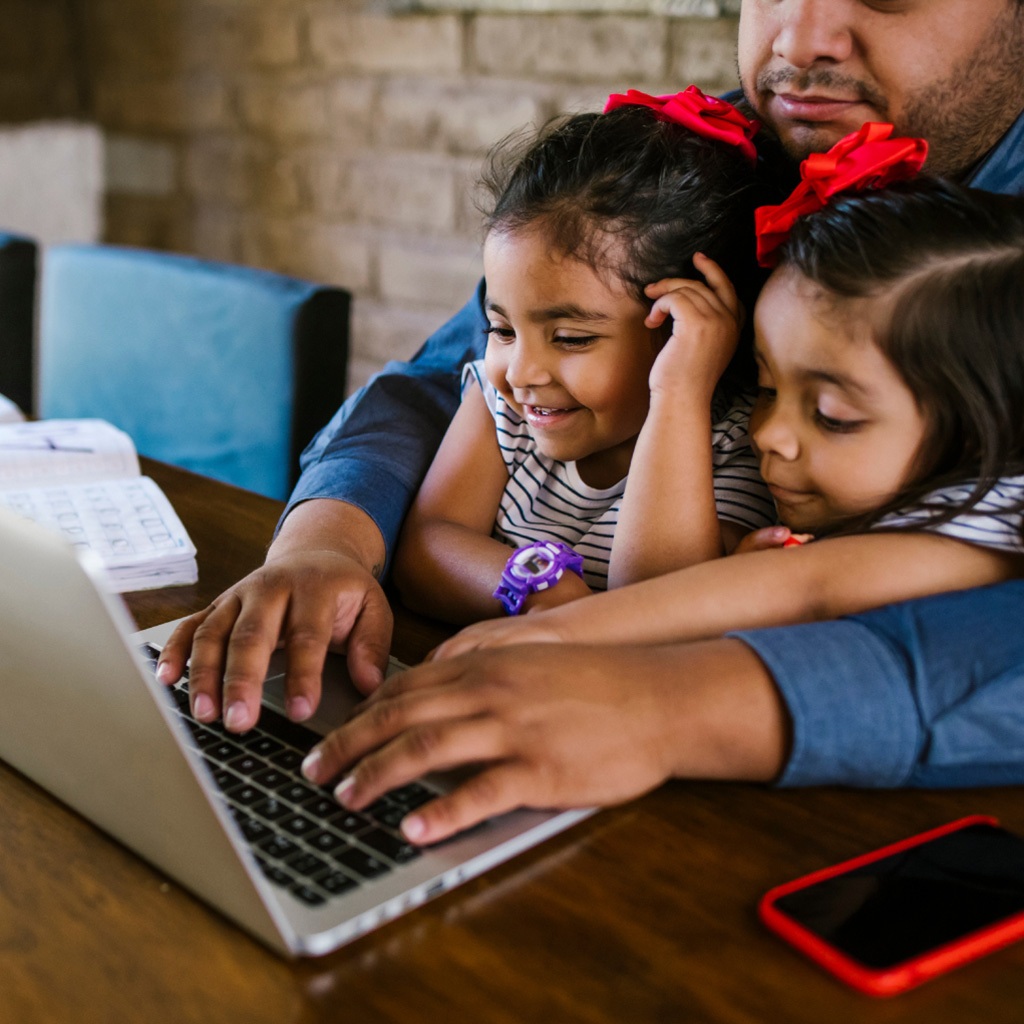 Man with toddlers on his lap looking at laptop