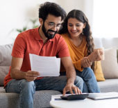 Couple sitting down and using a calculator.