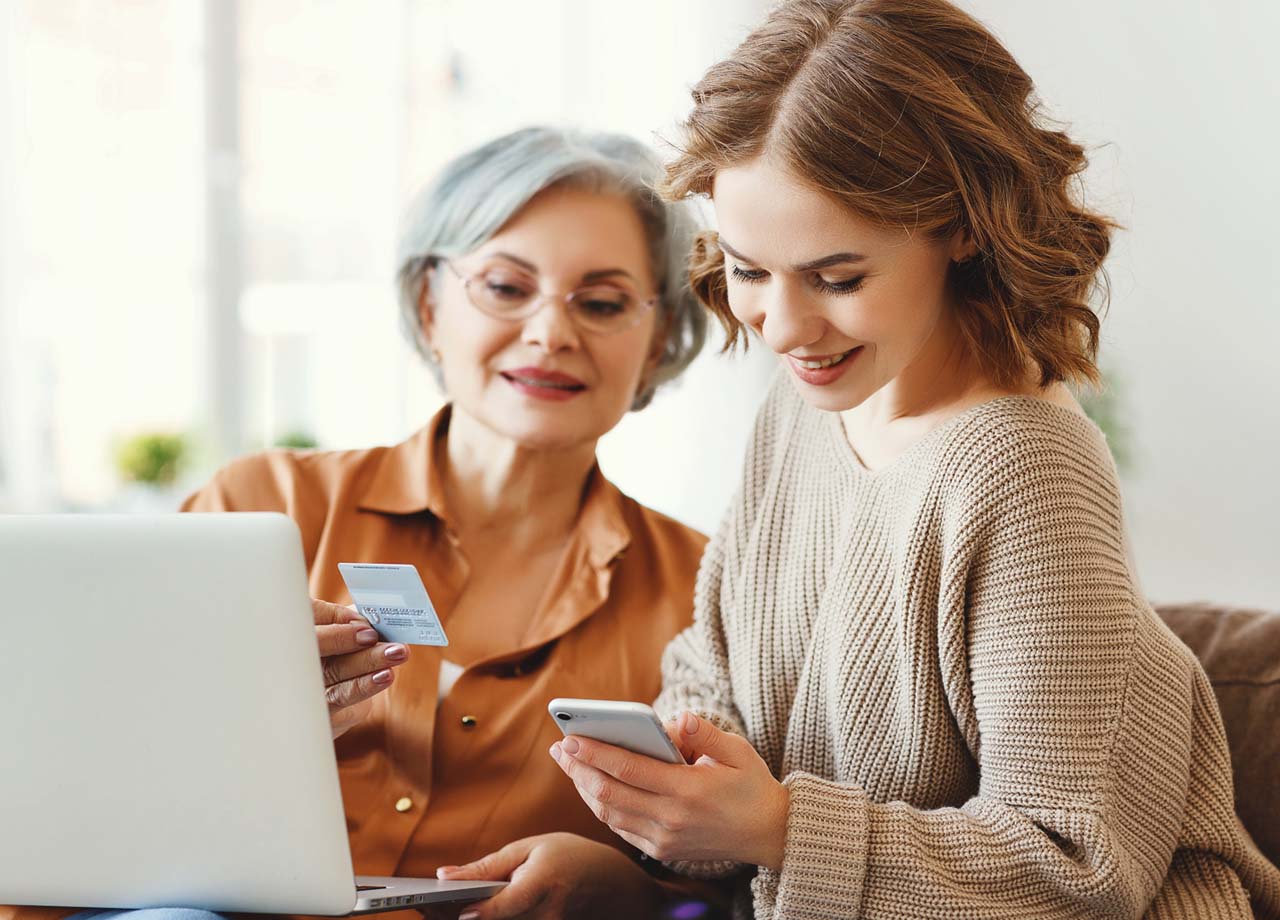 older woman looking at subscription card and younger woman looking at her phone