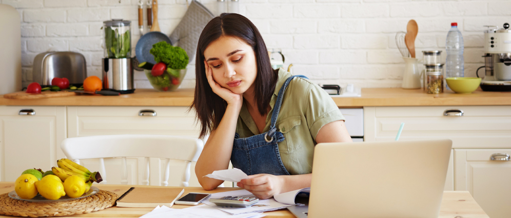 Woman standing in kitchen looking at bills