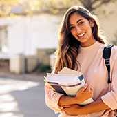 A young woman smiling holding books.