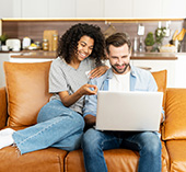Couple sitting on couch together looking at laptop