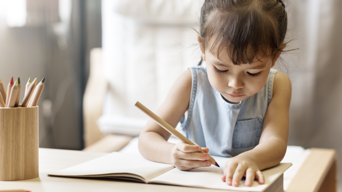 toddler girl writing in a notebook
