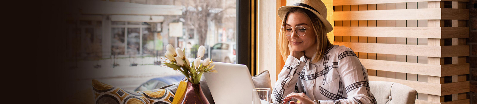 Woman with glasses sitting at a table in front of her laptop looking at her DCU eStatements