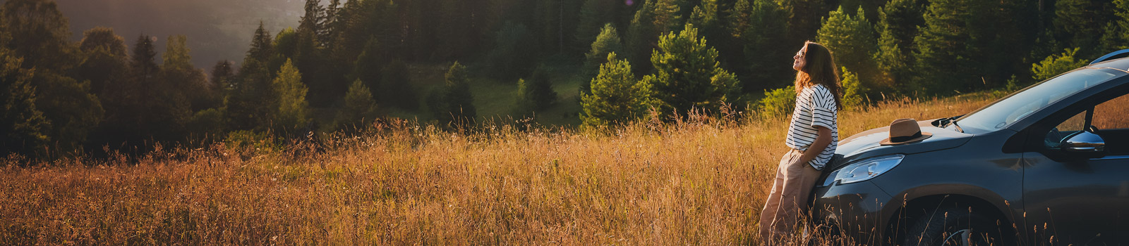 Woman leaning against her car in a meadow pondering her Guaranteed Asset Protection insurance offered at DCU