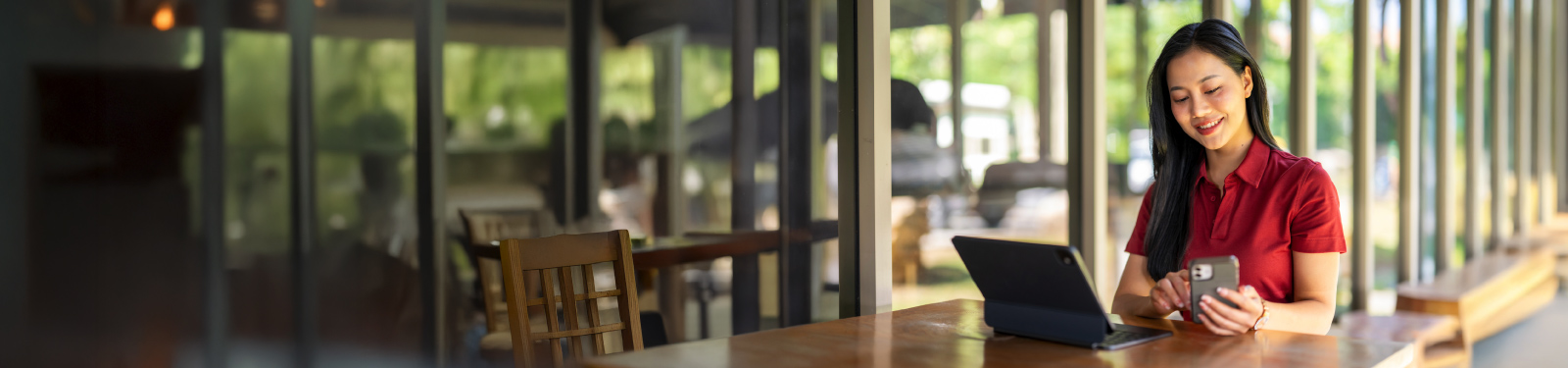 Woman sitting at a counter smiling at something on the tablet she is holding.