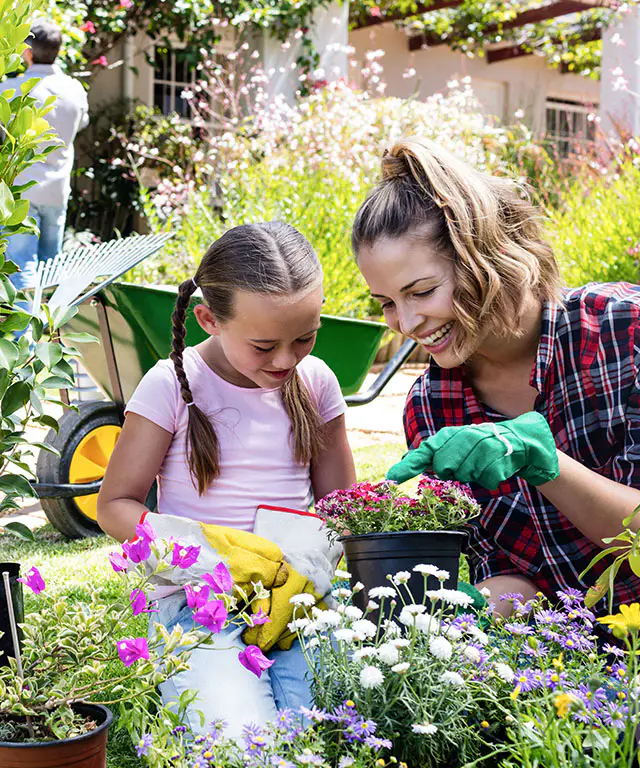 A mother and daughter smiling while gardening together.