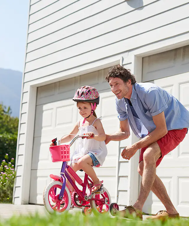 Dad teaching his daughter how to ride a bike