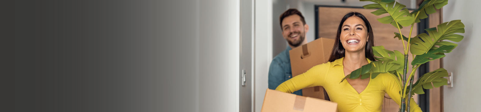 Man and woman with boxes moving into their new place and smiling.
