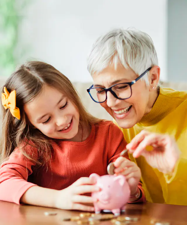 An adult and  child sit together indoors while looking at a small object on a table.