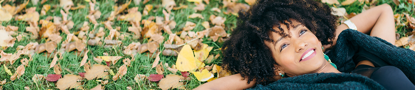 Image of a happy young woman lying on the grass