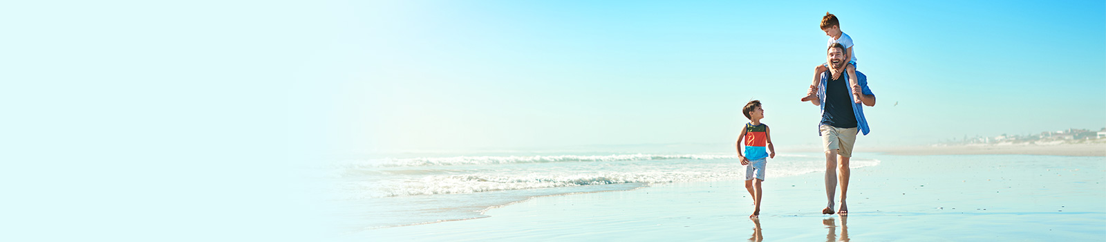 Father and sons walking on beach.