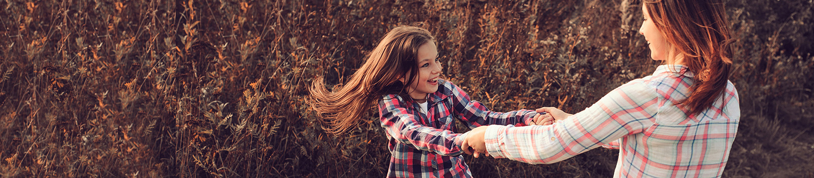 a young girl and an older girl holding hands and playing outdoors