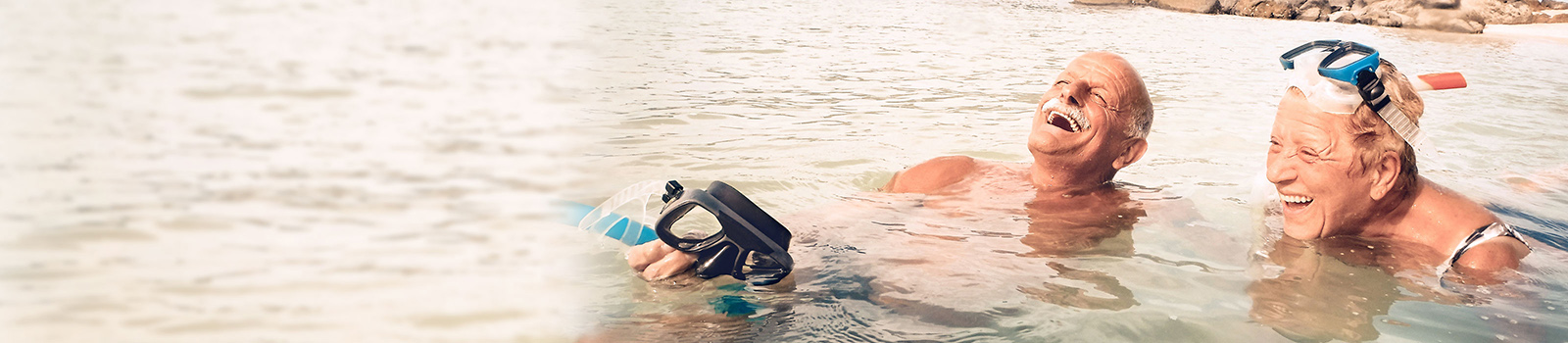 a happy old couple with snorkelling gear swimming and having a great time