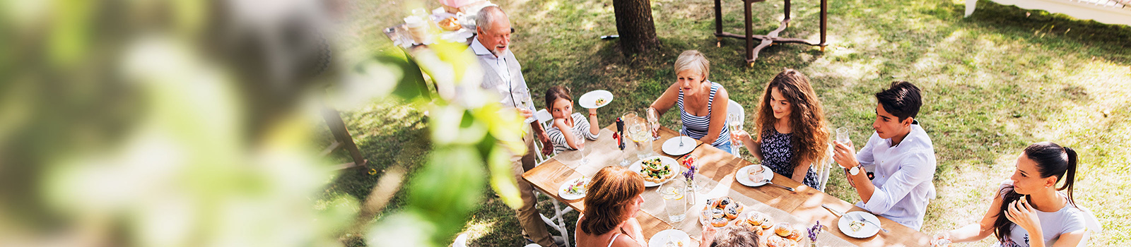 top shot of a big family sitting around a table and enjoying an outdoor lunch 