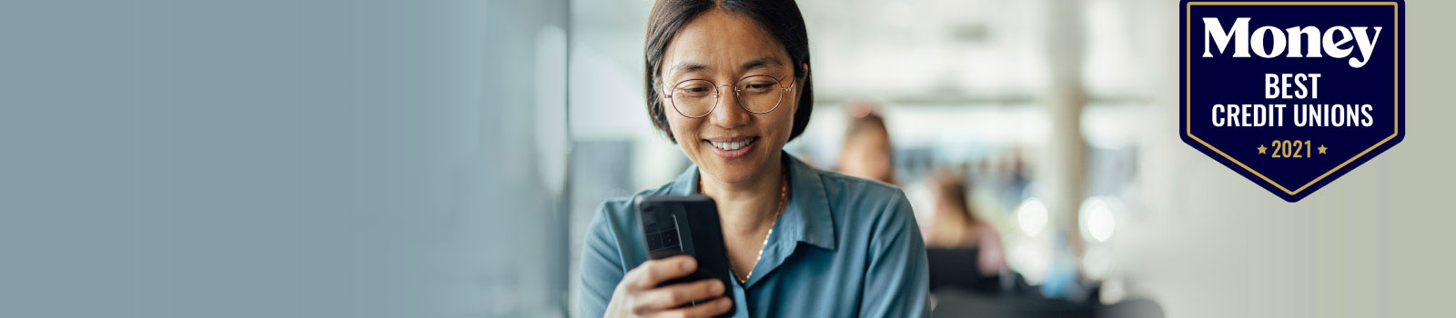 A woman smiling at her phone.