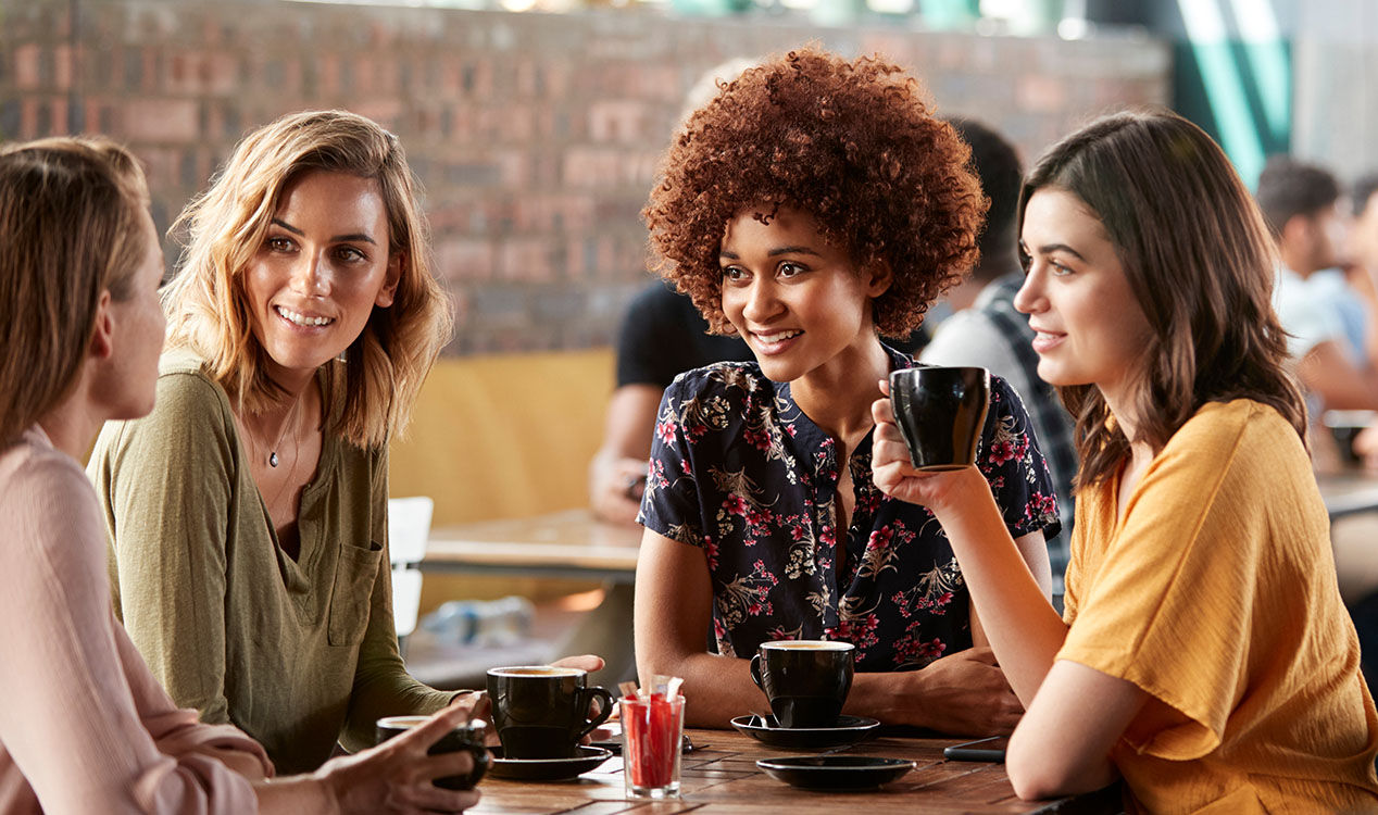 group of women sitting at a table drinking coffee