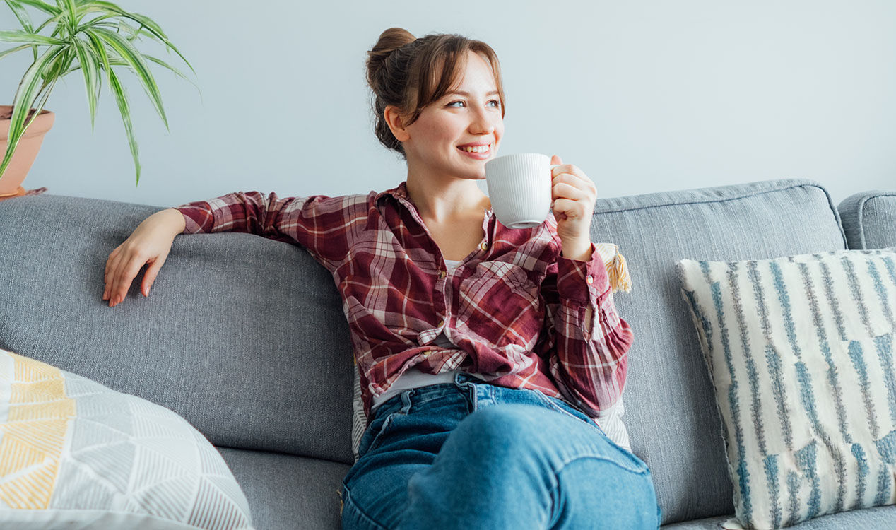 woman sitting on couch drinking coffee