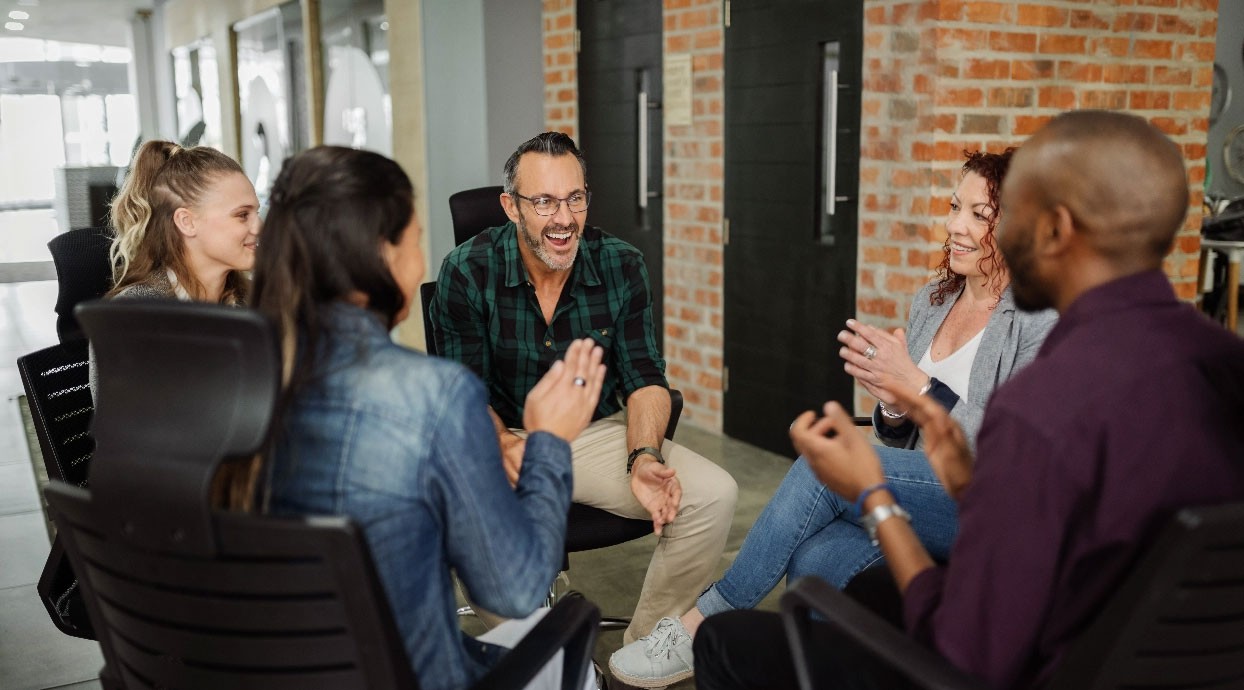 Men and Women sitting in chairs and having fun