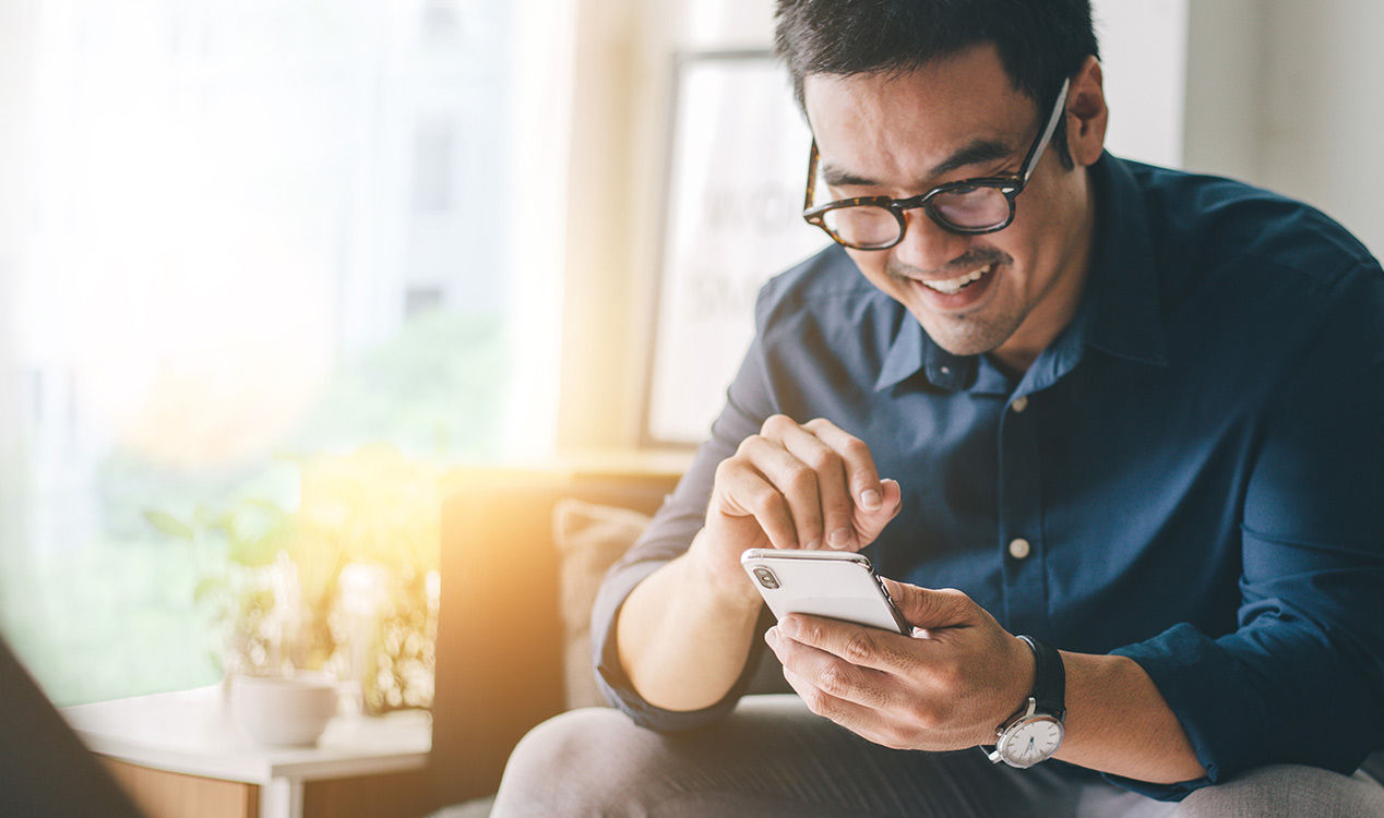 man using his phone while smiling